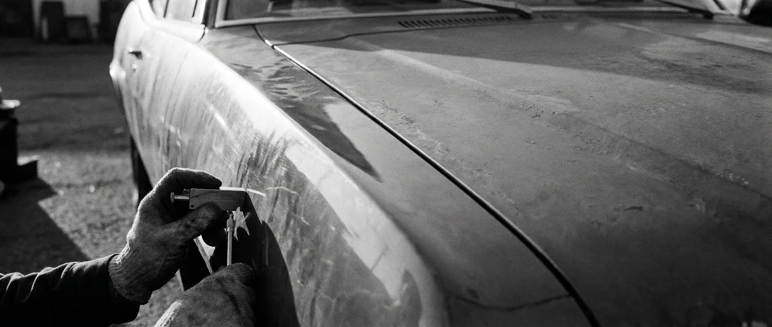 Paint depth gauge held against the front guard of an electric car
