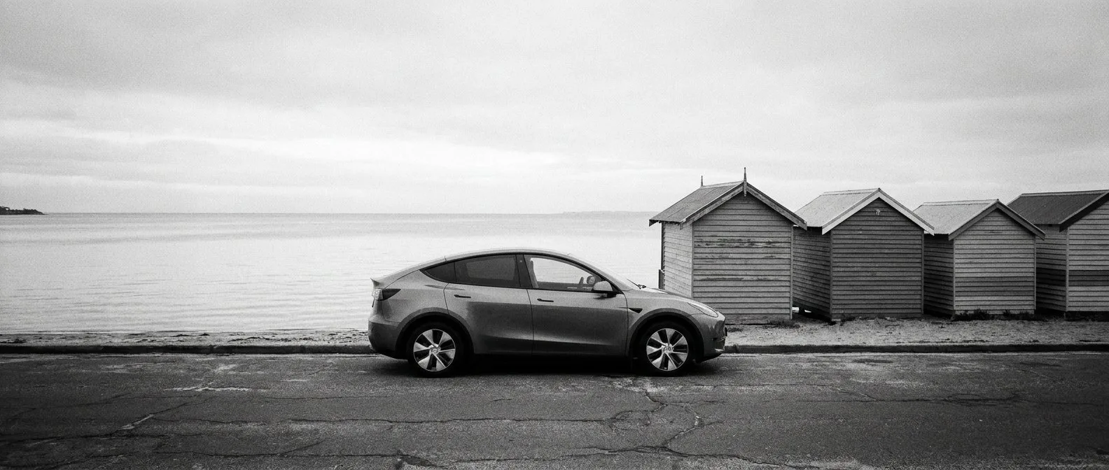 Electric car parked beside bathing boxes on the Bayside foreshore