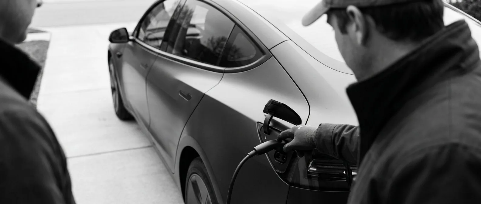 Technician pointing to the open charge port of a modern electric car