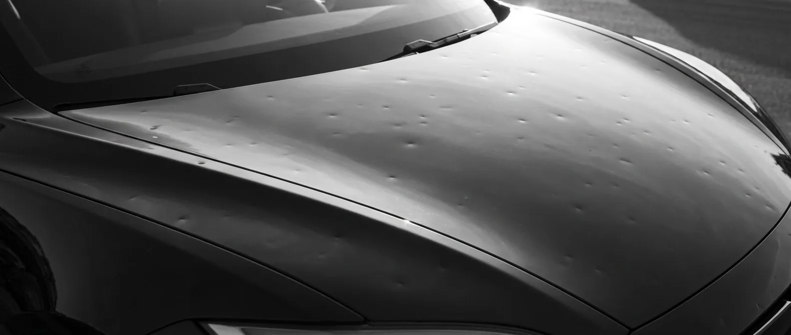 Shallow hail dents across the bonnet of a modern electric car