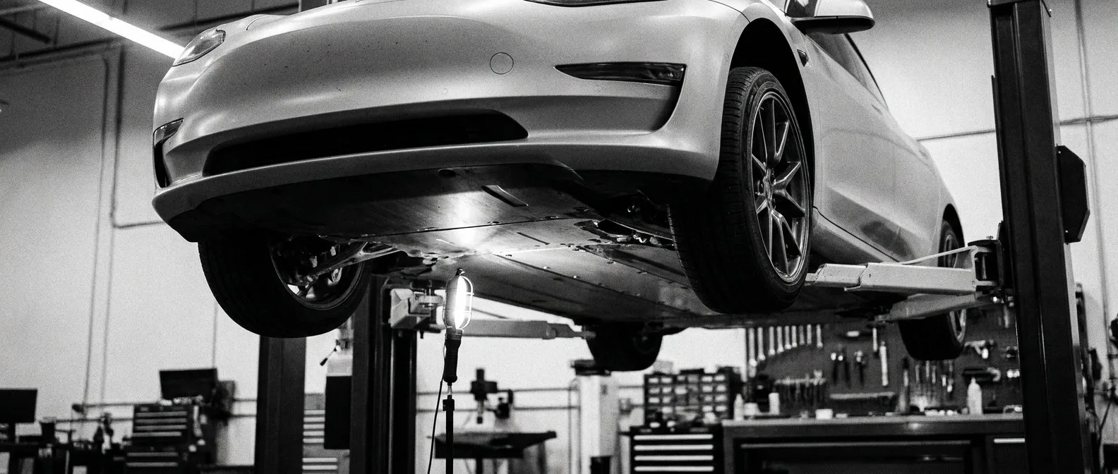 Electric sedan raised on a workshop hoist for inspection